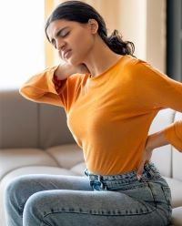Young woman wincing as she touches her lower back